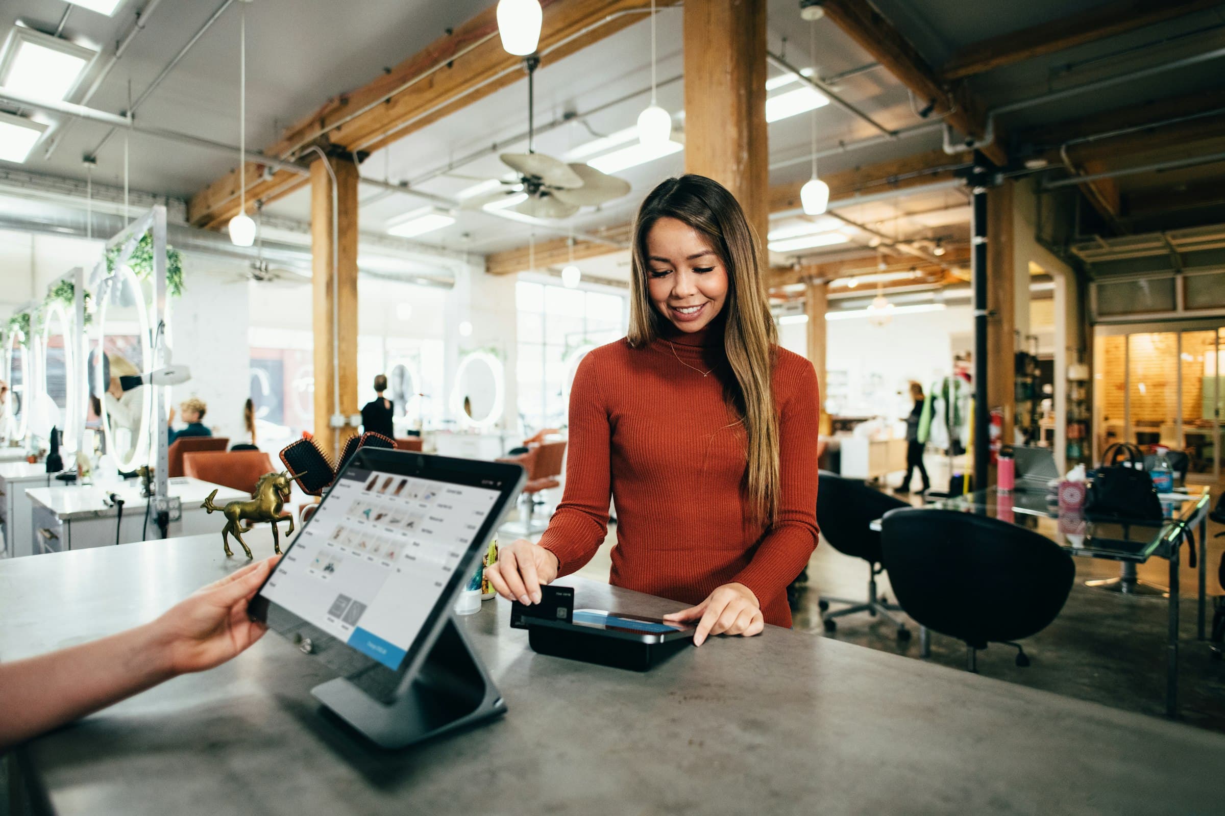A customer pays at the counter with a card terminal and a tablet register